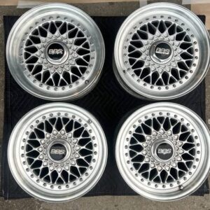 BBS RS three-piece forged split rim wheels featuring a raw silver finish, iconic cross-spoke pattern, polished stepped lips, and original black center caps with chrome BBS lettering