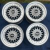 BBS RS three-piece forged split rim wheels featuring a raw silver finish, iconic cross-spoke pattern, polished stepped lips, and original black center caps with chrome BBS lettering