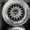 BBS RS three-piece forged split rim wheels featuring a raw silver finish, iconic cross-spoke pattern, polished stepped lips, and original black center caps with chrome BBS lettering