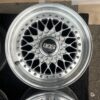 BBS RS three-piece forged split rim wheels featuring a raw silver finish, iconic cross-spoke pattern, polished stepped lips, and original black center caps with chrome BBS lettering