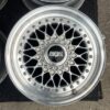 BBS RS three-piece forged split rim wheels featuring a raw silver finish, iconic cross-spoke pattern, polished stepped lips, and original black center caps with chrome BBS lettering