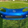 OEM Mazda MX-5 Miata (NB2 / 2001–2005) Front Bumper Cover Assembly in Laser Blue / OEM Blue, complete with fog lights, center grille mesh, emblem, and lower lip.