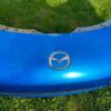 OEM Mazda MX-5 Miata (NB2 / 2001–2005) Front Bumper Cover Assembly in Laser Blue / OEM Blue, complete with fog lights, center grille mesh, emblem, and lower lip.