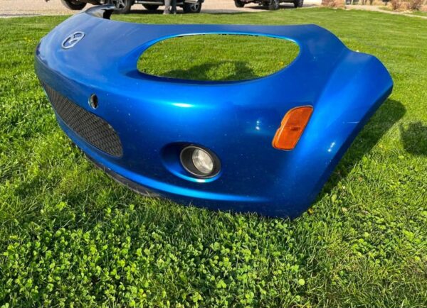OEM Mazda MX-5 Miata (NB2 / 2001–2005) Front Bumper Cover Assembly in Laser Blue / OEM Blue, complete with fog lights, center grille mesh, emblem, and lower lip.