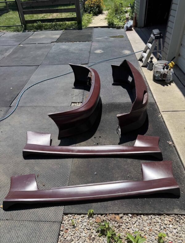 Screenshot 4-piece Full Aero Body Kit (Front Bumper, Rear Bumper, and Pair of Side Skirts) for the 1990–1997 Mazda MX-5 Miata (NA Generation), finished in dark burgundy/merlot paint.