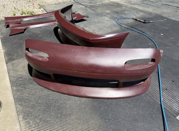 Screenshot 4-piece Full Aero Body Kit (Front Bumper, Rear Bumper, and Pair of Side Skirts) for the 1990–1997 Mazda MX-5 Miata (NA Generation), finished in dark burgundy/merlot paint.